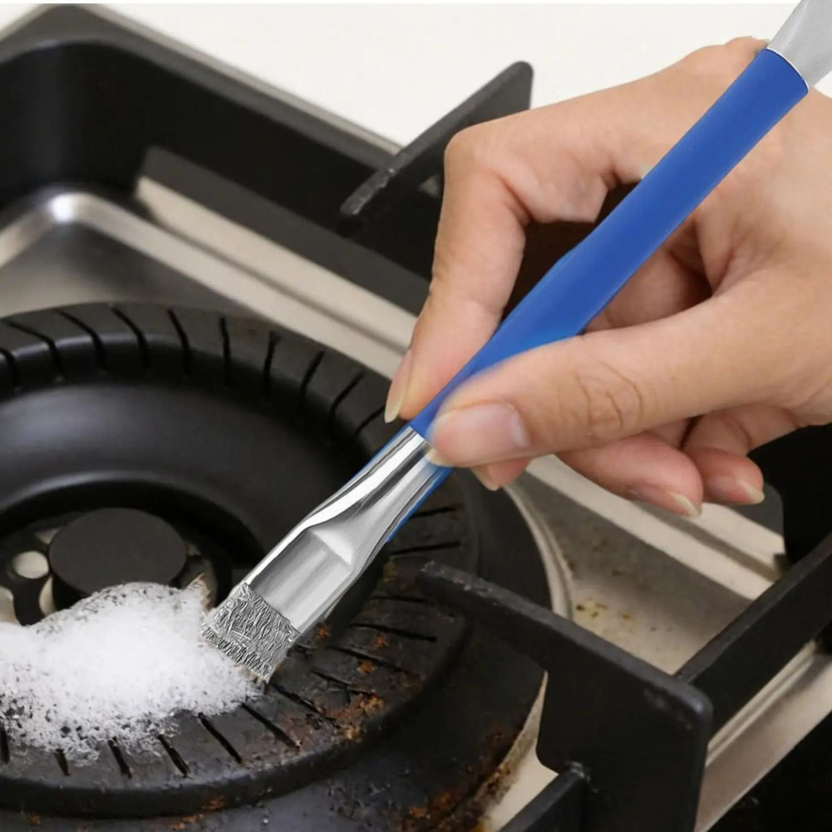 Une brosse métallique en acier inoxydable à double tête dans la main d'une femme qui nettoie un rond noir