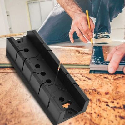 Une boîte à onglets pour plinthes posée sur un plancher à côté d’un homme