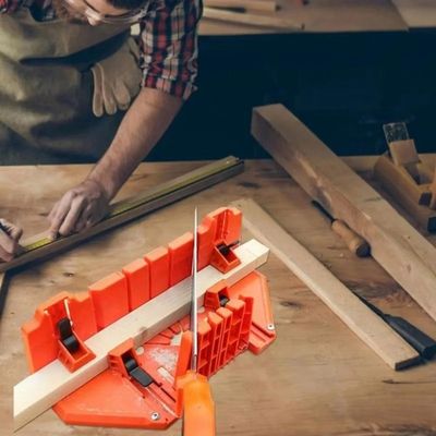 Une boîte à onglets pour plinthes de 14 pouces sur un établi, à côté d'un homme