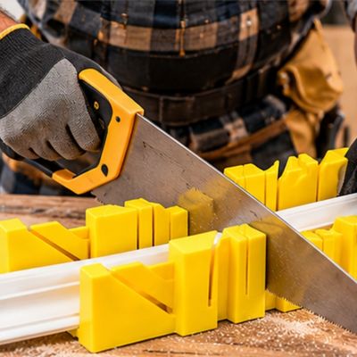 Une boîte à onglets pour plinthes 45 à 90 degrés jaune stabilisant une scie
