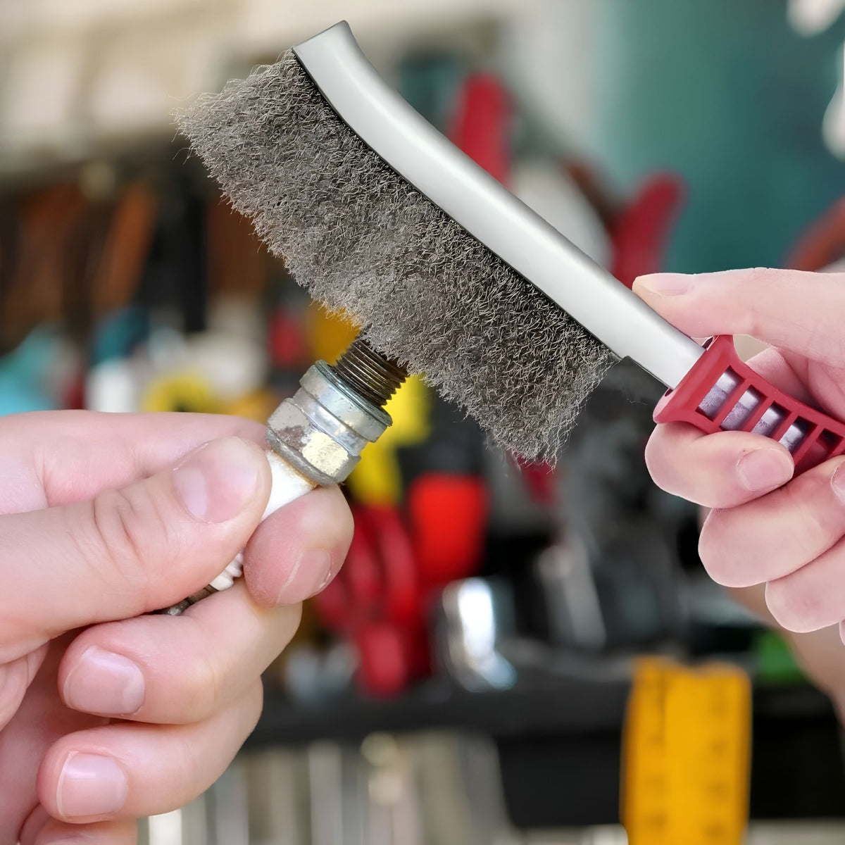 Une brosse métallique en acier inoxydable dans la main d'un homme qui enlève la rouille d'une bougie