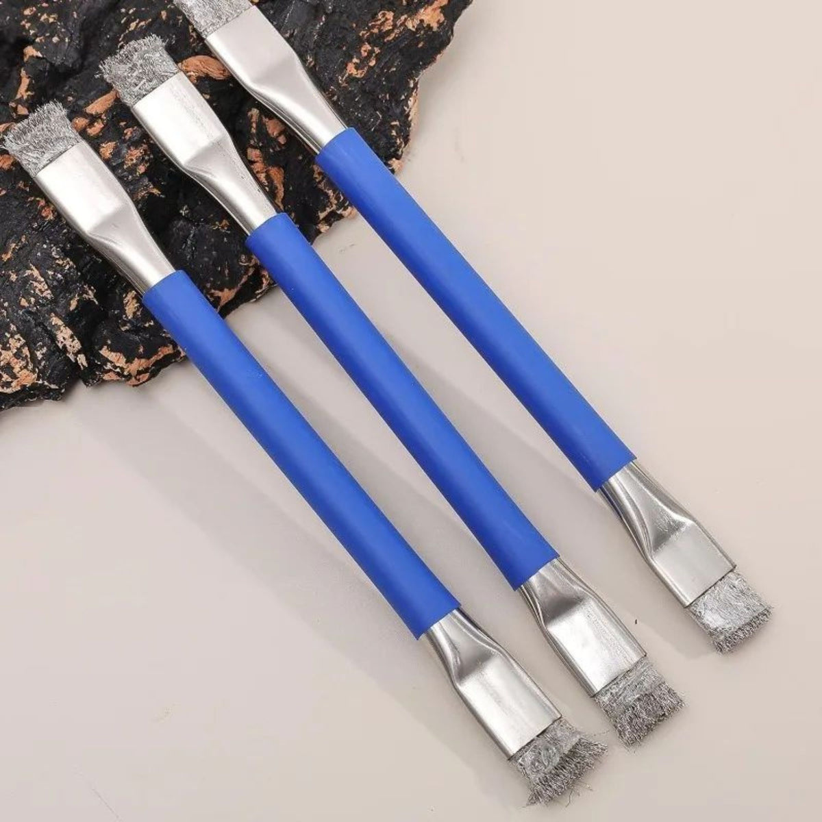 trois brosses métalliques dont on voit le bout et le manche bleu