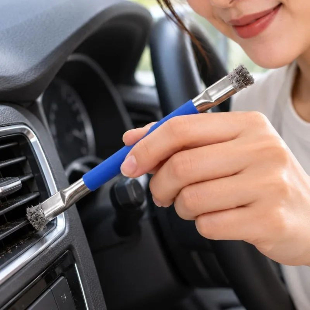Une brosse métallique en acier inoxydable à double tête dans la main d'une femme qui nettoie sa voiture