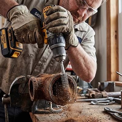 Brosses métalliques d'alésage en acier inoxydable dans la main d'un homme qui brosse un tuyau en acier