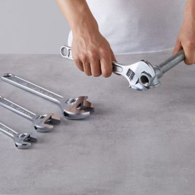 Une clé anglaise lot de 2 de 200 mm et 250 mm dans la main d'un homme qui visse un raccord de tuyau