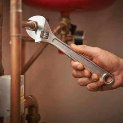 Une clé anglaise lot de 2 de 250 mm et 300 mm dans la main d'un homme qui visse un tuyau de cuivre