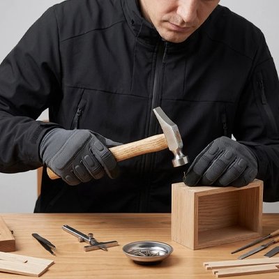 Marteau de cordonnier dans la main d'un homme qui cogne sur un clou pour assembler une planche de bois